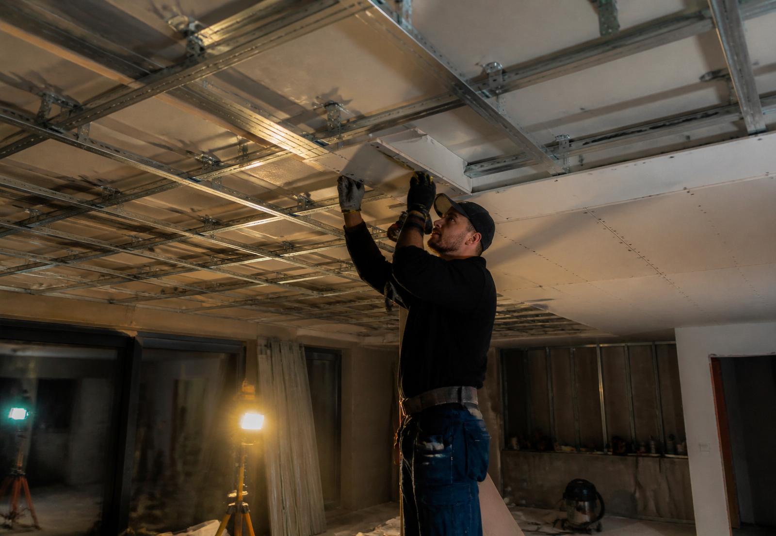Profissional instalando estrutura de drywall com perfis F530 em teto residencial